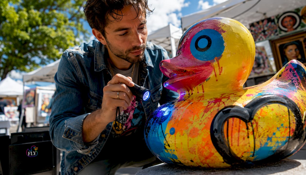 Art appraiser inspecting pop art sculpture under daylight and blacklight