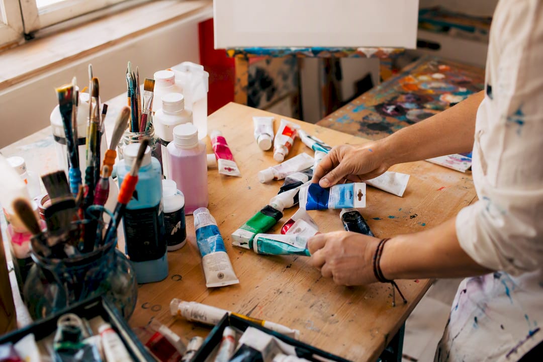 Hands arranging adaptive art supplies on table