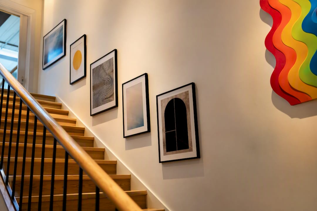 Curated artwork climbing a sloped staircase wall