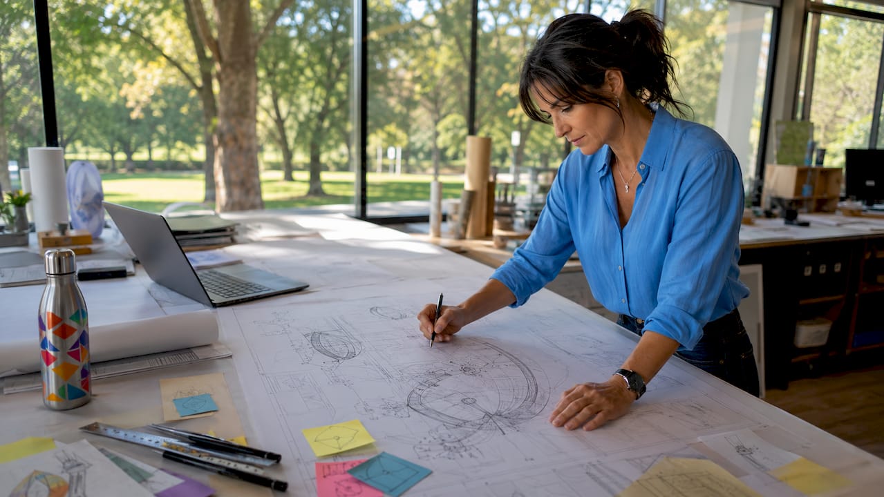 Engineer reviewing large blueprint at drafting table