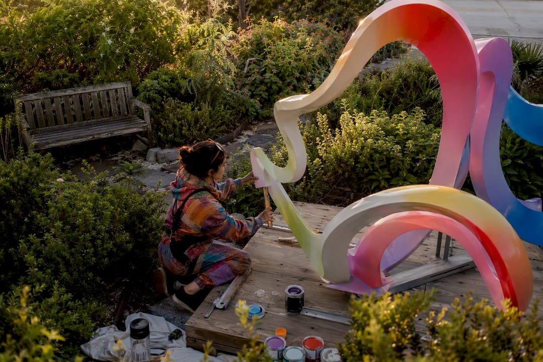 Artist installing site-specific sculpture outdoors